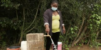 Josephine Mbayo uses one of the newly installed taps in Tongogara refugee camp to fill a bucket of water. The taps are part of a piped water system that uses solar power and high-capacity boreholes. © UNHCR/Tsvangirayi Mukwazhi