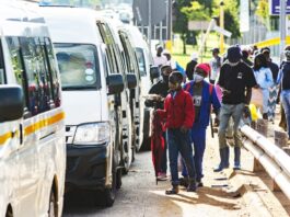 Commuters wear protective face masks as they line up for taxi vans in Pretoria, South Africa, on Feb. 8, 2021. WALDO SWIEGERS/BLOOMBERG