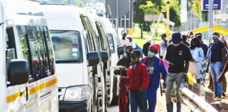 Commuters wear protective face masks as they line up for taxi vans in Pretoria, South Africa, on Feb. 8, 2021. WALDO SWIEGERS/BLOOMBERG