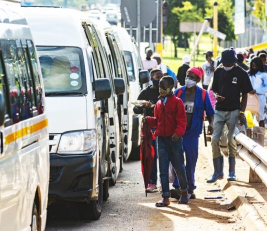 Commuters wear protective face masks as they line up for taxi vans in Pretoria, South Africa, on Feb. 8, 2021. WALDO SWIEGERS/BLOOMBERG