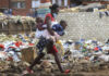 A woman carrying two children walks past a garbage dump amid the third wave of the Covid-19 pandemic in Harare, Zimbabwe on 21 April 2021. (Photo: EPA-EFE / Aaron Ufumeli)